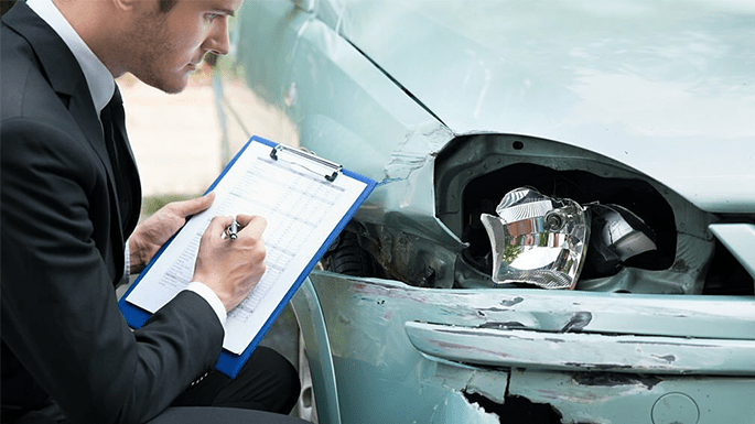 insurance agent inspecting a damaged car